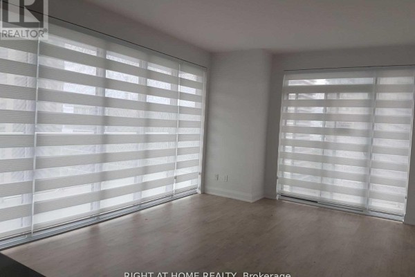 Living room featuring striped blinds on large windows and sliding glass doors with city views. - 1703 - 56 Annie Craig Drive, Toronto