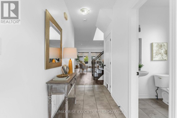 Foyer with console table, lamp, artwork, and view of living area and staircase. - 1704 Reginald Bart Drive, Kingston)