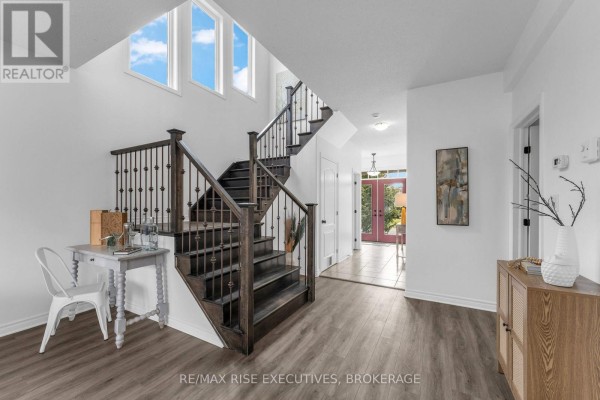 Wide view of the foyer, showcasing a dark wood staircase, desk, and entryway. - 1704 Reginald Bart Drive, Kingston)