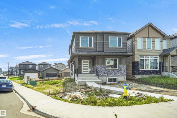 Exterior front view of a grey two-story house with stone accents and a concrete walkway. - 17040 47 St Nw, Edmonton