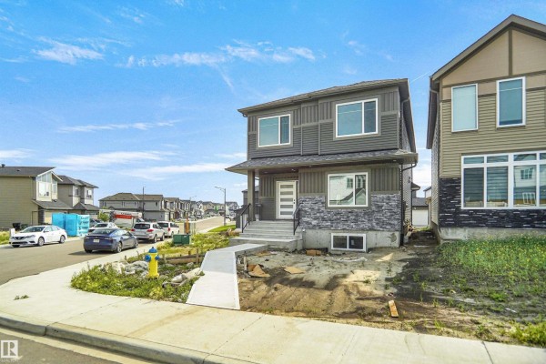 Exterior front view of a grey two-story house with stone accents and a concrete walkway. - 17040 47 St Nw, Edmonton