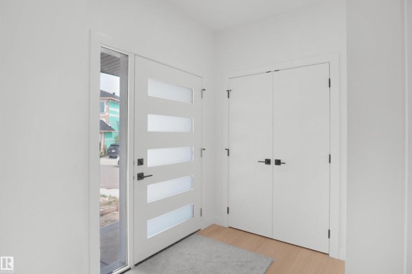 Interior entryway with a white front door with frosted glass panels and double white closet doors. - 17040 47 St Nw, Edmonton