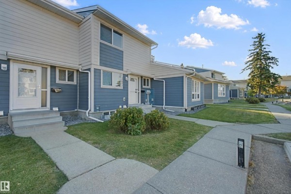 Side view of townhouses with blue and tan siding and manicured lawns. - 17041 100 St Nw, Edmonton