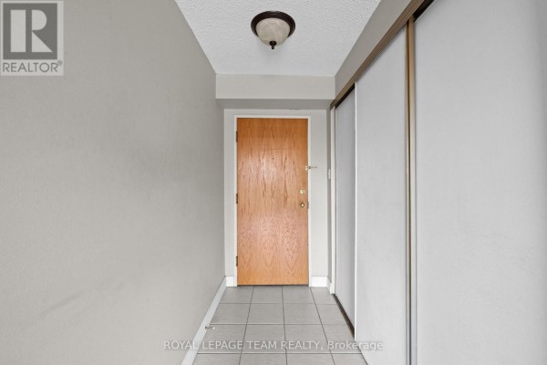 Apartment entryway with a light wood door, tile floor, and closet. - 1705 - 199 Kent Street, Ottawa
