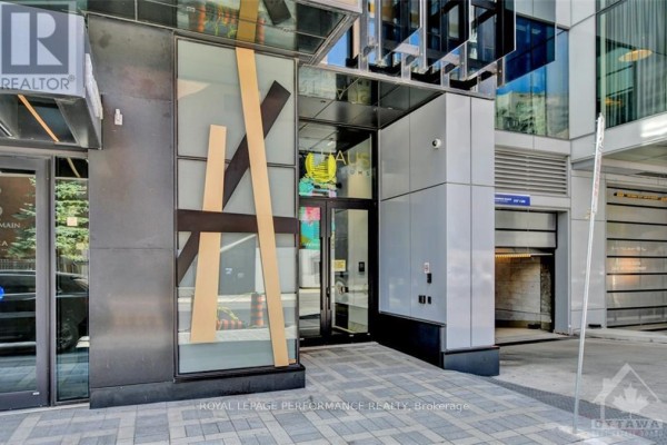 Entrance to the modern apartment building with glass doors and grey accents. - 1705 - 20 Daly Avenue, Ottawa