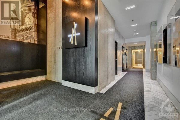 Interior hallway of the apartment building with dark wood paneling and concrete walls. - 1705 - 20 Daly Avenue, Ottawa