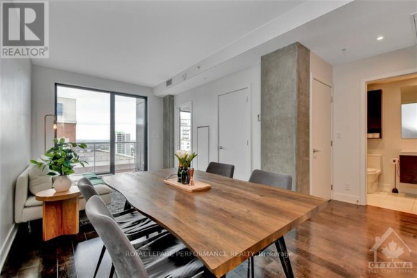Apartment dining area with a live-edge wood table, grey chairs, and city view from balcony doors. - 1705 - 20 Daly Avenue, Ottawa