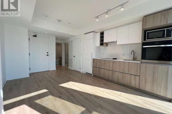 View of the open-concept living space, kitchen, and hallway leading to bathroom. - 1705 - 319 Jarvis Street, Toronto