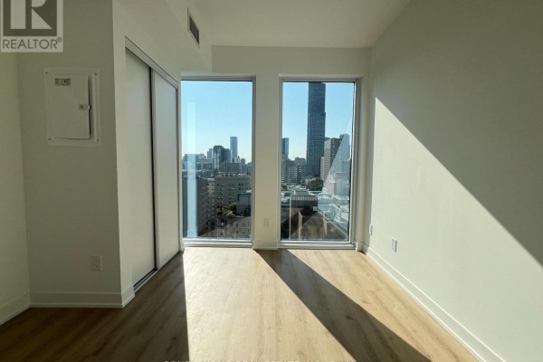 Bedroom with two large windows offering a panoramic view of the city skyline. - 1705 - 319 Jarvis Street, Toronto