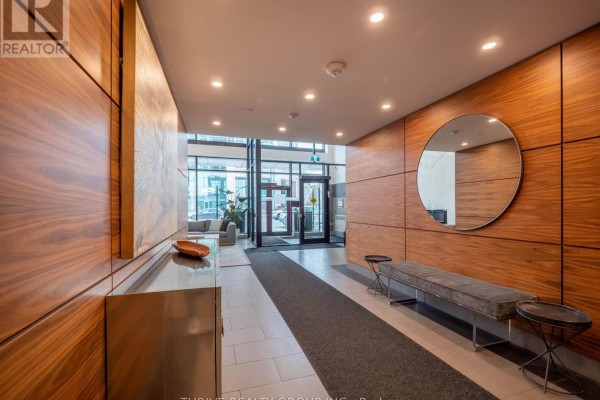 Entrance hallway with wooden paneling, a round mirror, and a bench. - 1705 - 505 Talbot Street, London East