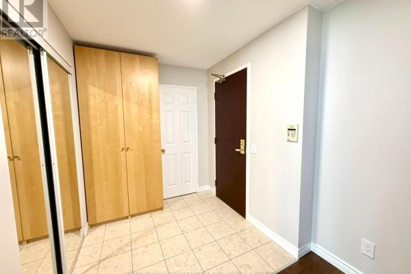 Apartment entrance hallway with tiled floor, wooden closet, and dark wood door. - 1706 - 18 Parkview Avenue, Toronto