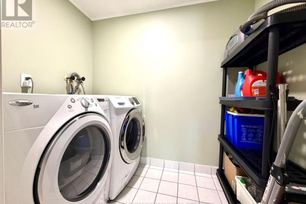 Laundry room with white washer and dryer, plus a black plastic shelving unit. - 1706 - 18 Parkview Avenue, Toronto