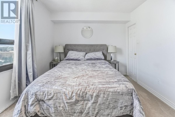 Bedroom with a queen-sized bed, grey headboard, bedside tables, and a window view. - 1706 - 20 Mississauga Valley Boulevard, Mississauga