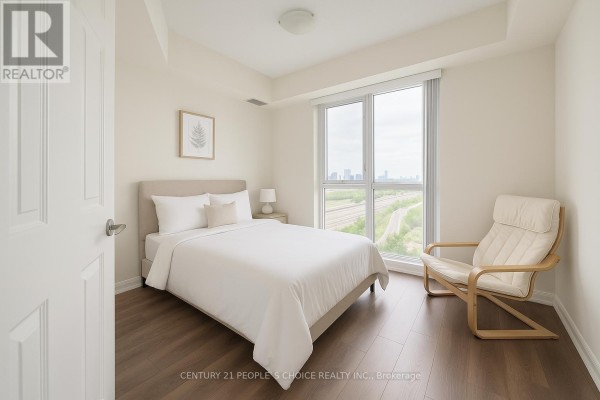 Bedroom with a queen-size bed, light wood chair, and large window overlooking an urban landscape. - 1706 - 349 Rathburn Road W, Mississauga