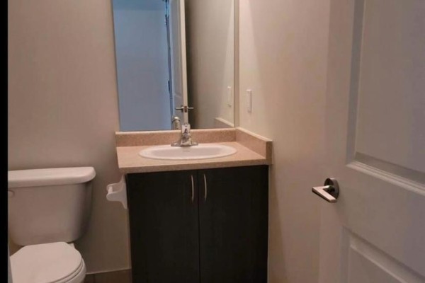 Powder room with a toilet, vanity with sink, dark wood cabinet, and a mirror. - 1706 - 349 Rathburn Road W, Mississauga