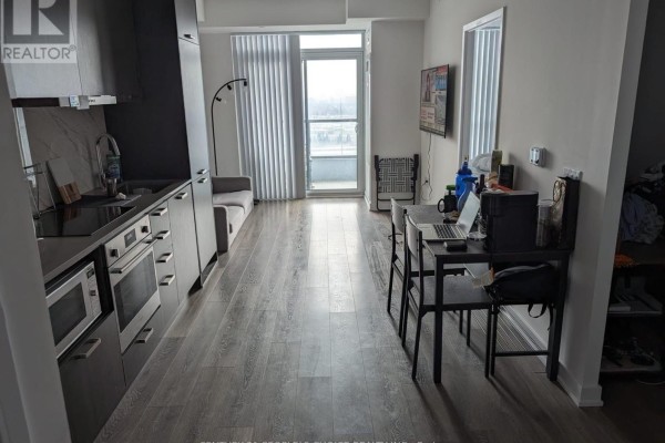 Apartment living area with grey flooring, sofa, dining table, and balcony access. - 1706 - 38 Honeycrisp Crescent, Vaughan