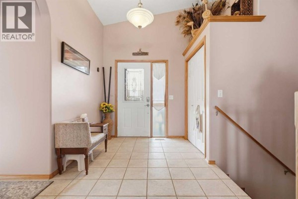 Interior entryway with beige walls, tiled floor, and a white front door with decorative glass. - 1706 3 Avenue Se, High River