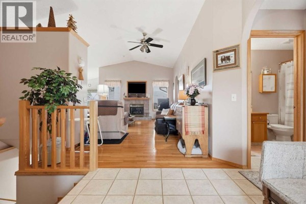 View from entryway into a living room with a fireplace and a bathroom with a toilet. - 1706 3 Avenue Se, High River