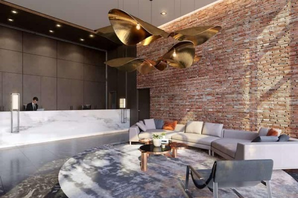 Building lobby with a marble reception desk, brick wall, and seating area. - 1707 - 286 Main Street, Toronto
