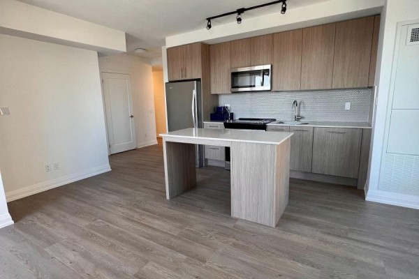 Open concept living area with a kitchen island and light wood flooring. - 1707 - 286 Main Street, Toronto