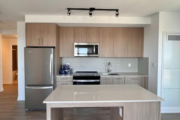 Kitchen with stainless steel appliances, light wood cabinetry, and island. - 1707 - 286 Main Street, Toronto