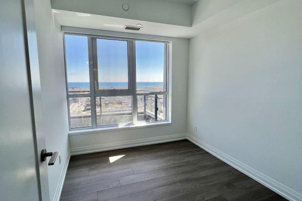 Empty bedroom with a large window overlooking the city and water. - 1707 - 286 Main Street, Toronto