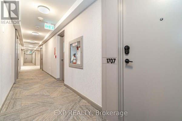 Apartment building lobby with seating areas, decorative elements, and large windows with sheer curtains. - 1707 - 4675 Metcalfe Avenue, Mississauga