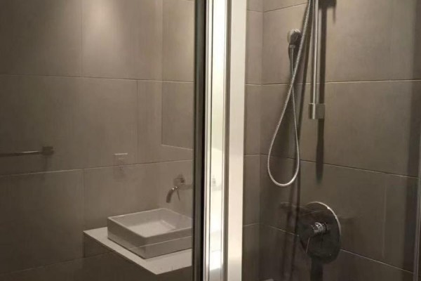 A modern bathroom with large grey tiles, a floating sink, and a glass-enclosed shower. - 1708 - 159 Dundas Street E, Toronto