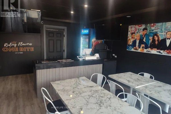 Restaurant interior with a black counter, two marble-top tables, and a Pepsi fridge. - 1708 Eglinton Avenue W, Toronto