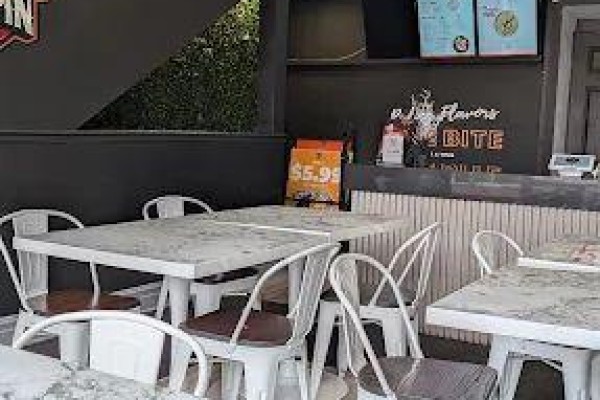 Dining area with marble-top tables and white chairs, near a service counter and menu boards. - 1708 Eglinton Avenue W, Toronto