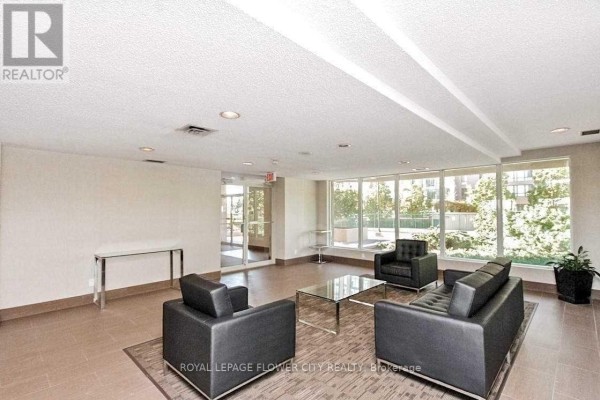 Building lobby with black leather sofas, glass coffee table, glass console table, and large windows. - 1709 - 115 Hillcrest Avenue, Mississauga