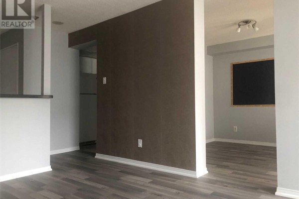 View of an apartment's interior with grey walls, dark wood laminate flooring, and a brown accent wall. - 1709 - 115 Hillcrest Avenue, Mississauga