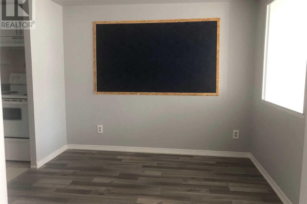 Dining area with grey walls, dark wood laminate flooring, and a large black chalkboard with a wooden frame. - 1709 - 115 Hillcrest Avenue, Mississauga