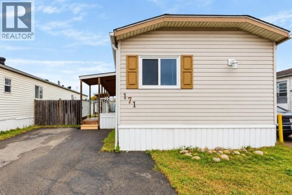 Close-up side view of a beige mobile home with beige siding and a covered porch. - 171 Grant Way, Fort Mcmurray