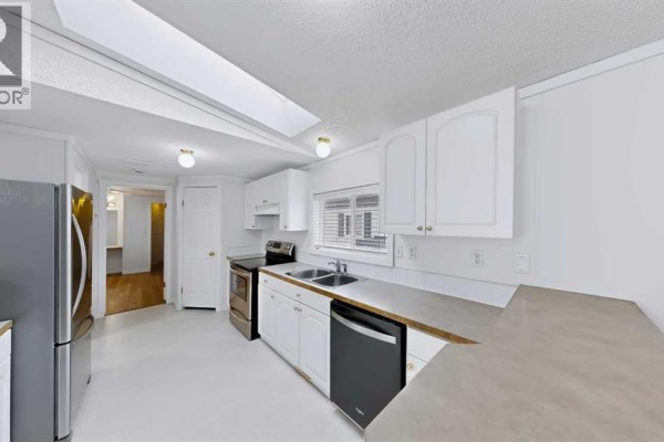 Bright white kitchen with stainless steel appliances, light grey countertops, and a skylight. - 171 Grant Way, Fort Mcmurray