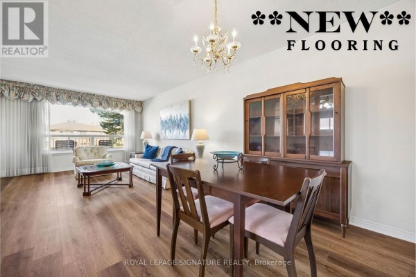 Dining area with a wooden table, upholstered chairs, and a partial view of a living room. - 171 Petworth Crescent, Toronto