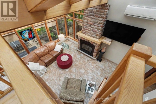 View from above of a sunroom featuring a stone fireplace, leather sofa, and glass ceiling. - 171 Powell Avenue, Ottawa