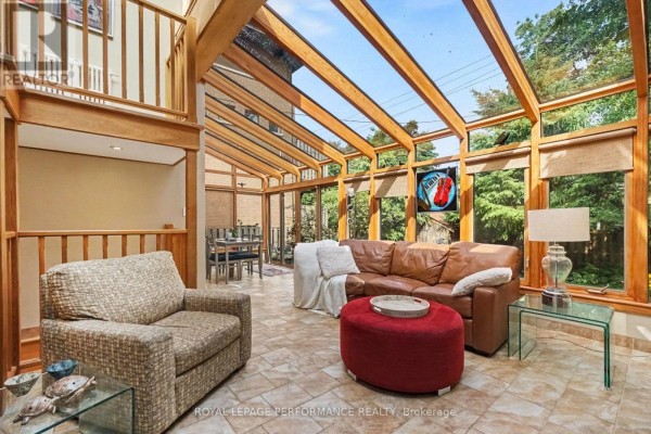 Bright sunroom with a leather sofa, fireplace, and large windows with wooden trim and blinds. - 171 Powell Avenue, Ottawa