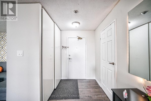 Apartment entrance hallway with white closet doors, a white front door, and dark wood-look flooring. - 1710 - 5 Rowntree Road, Toronto