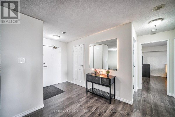 Apartment hallway with white closet doors, a white front door, dark wood-look flooring, and a large mirror. - 1710 - 5 Rowntree Road, Toronto