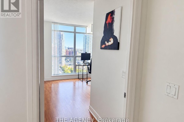 Bedroom with a walk-in closet on the left and a queen bed with white bedding on the right. - 1711 - 35 Bales Avenue, Toronto