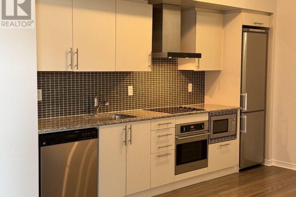 Kitchen with light beige cabinetry, granite countertops, stainless steel appliances, and a mosaic tile backsplash. - 1711 - 352 Front Street W, Toronto