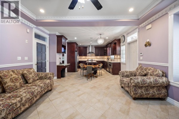 Open-concept living area with two floral sofas, a kitchen with dark wood cabinets and island. - 1711 Sixth Avenue, New Westminster