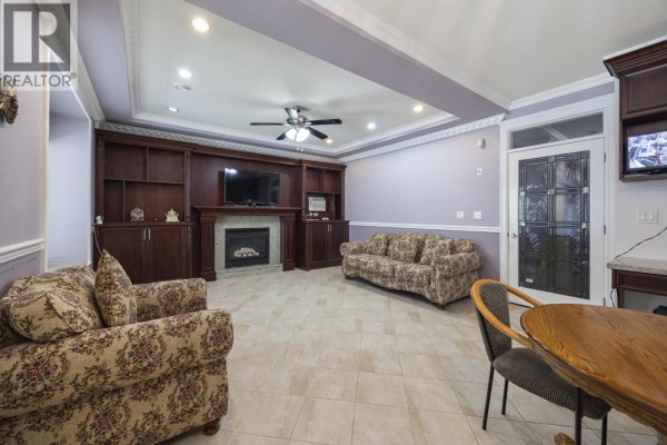 Living room with fireplace, built-in entertainment unit, floral sofa, and a dining table. - 1711 Sixth Avenue, New Westminster