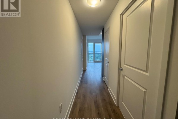 Hallway inside an apartment with light grey walls, wood floors, and white doors. - 1711a - 115 Nipissing Road N, Milton