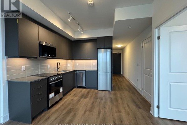 Apartment kitchen with dark grey cabinets, stainless steel appliances, and wood floors. - 1711a - 115 Nipissing Road N, Milton
