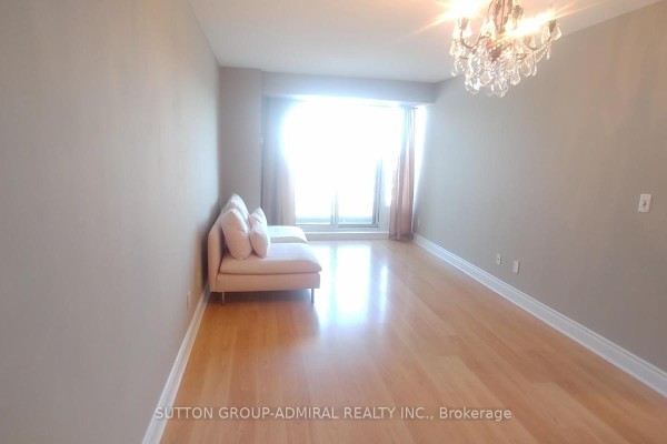 Living room with light wood floors, beige walls, a pink sofa, and a large window. - #1712 - 7 North Park Road, Vaughan