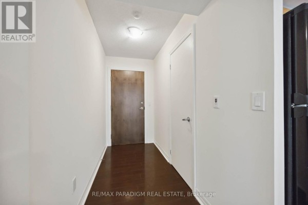 A short, brightly lit apartment hallway with dark wood floors and white walls. - 1713 - 16 Yonge Street, Toronto