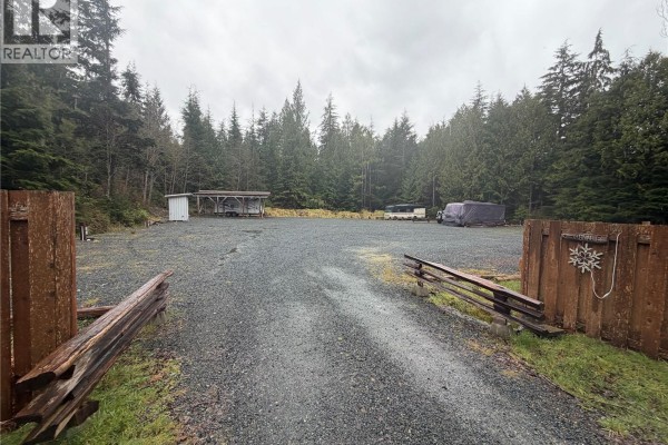 Interior shot of a cabin showing a bed, compact kitchen area with microwave and mini-fridge, and a TV. - 17161 Parkinson Rd, Port Renfrew
