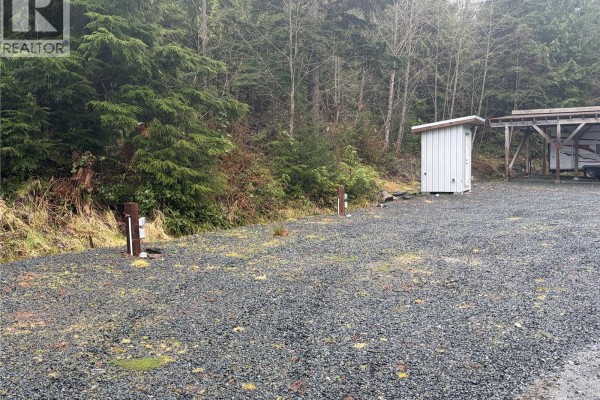 Interior cabin view with a bed, small dining table, kitchen counter with microwave, and built-in cabinets. - 17161 Parkinson Rd, Port Renfrew